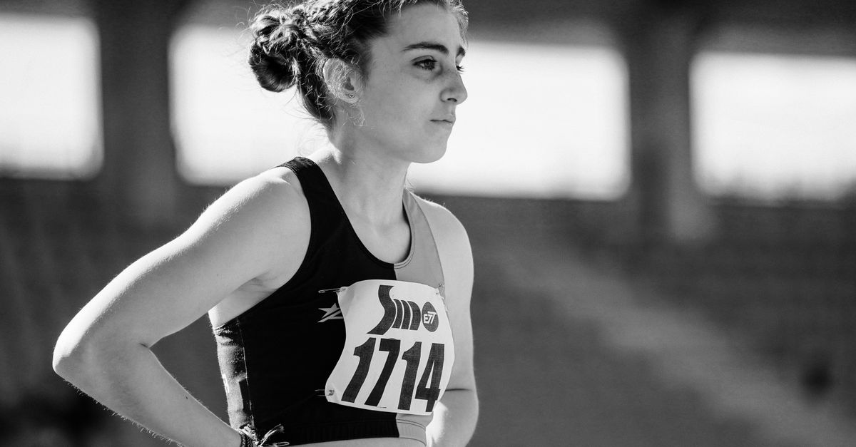 Black and white photo of a female athlete focused before a track competition, wearing bib number 1114.